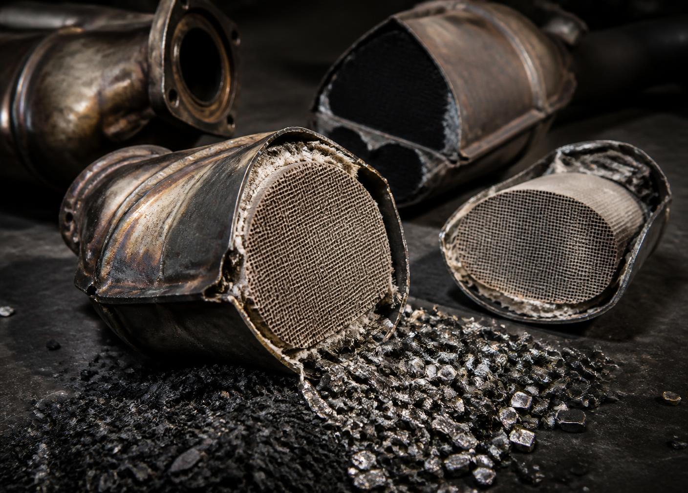 Used ceramic and metallic catalytic converters cut open on a workbench